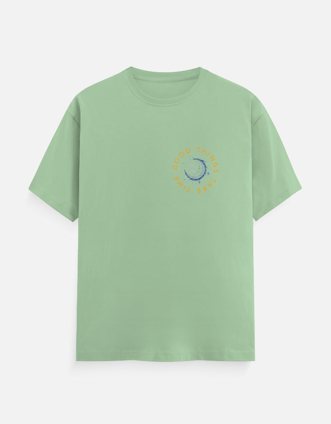 Light green t-shirt featuring a circular blue moon graphic with 'Good Things Take Time' text.